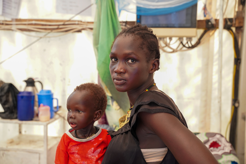 Nya Sibet Mar is holding her two-year-old daughter, Nya Thor, who is suffering from severe malaria