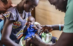 Medical staff inoculating malaria vaccine to a baby girl