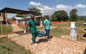 At the Marburg treatment unit, two staff of the Ministry of Health moving a basin of used gum boots to be disinfected in the laundry, a semi-permanent facility built by MSF to improve the infection prevention and control during this Marburg outbreak.