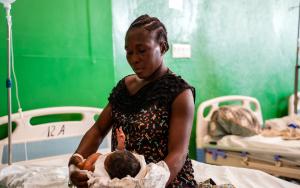 Resimène, 39 y.o, is holding her new-born baby on her bed in the MSF supported Isaïe Jeanty Maternity in Port-au-Prince