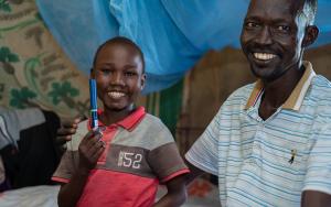 Aher Lual, 11, holds an insulin pen next to his father in their home in Ariath, Aweil North. He prefers the pen to the vial injections he used before.