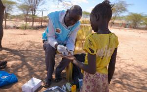 David Ekeru, a community health promoter, tests a child for malaria at their home using the test and treat approach in Namakane village, Turkana, Kenya.