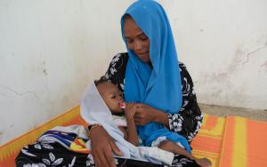 After receiving Plumpy’Nut at the Amsinéné health center supported by MSF for nutritional care, this mother gives the Plumpy’Nut to her daughter.