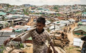 A Rohingya man carries wood through the Kutupalong- Balu Khali mega camp. Cox’s Bazar District, Bangladesh. [© Robin Hammond/NOOR ]