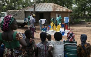 Villagers watch a WatSan prepare for the disinfection of a house in Ndiovu village