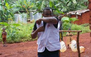 Tumaini Kombe, focal point for health promotion in Nduta explaining sneeze & cough etiquette