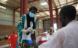 An MSF nurse, Regina Joseph, takes a blood sample for a rapid malaria test for Masakeel Deng,