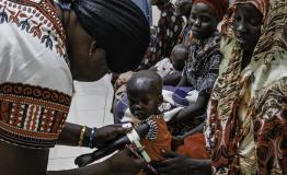 Malnutrition screening of one-year-old Alnel on the knees of his mother Nyanbeny. Ameth Bek Hospital, Abyei.