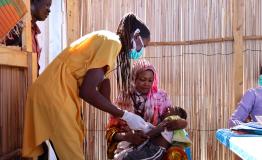 Halima is holding her daughter Aszed during vaccination