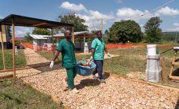 At the Marburg treatment unit, two staff of the Ministry of Health moving a basin of used gum boots to be disinfected in the laundry, a semi-permanent facility built by MSF to improve the infection prevention and control during this Marburg outbreak.