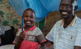 Aher Lual, 11, holds an insulin pen next to his father in their home in Ariath, Aweil North. He prefers the pen to the vial injections he used before.