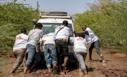 MSF staff pushing a vehicle that got stuck in the mud