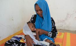 After receiving Plumpy’Nut at the Amsinéné health center supported by MSF for nutritional care, this mother gives the Plumpy’Nut to her daughter.