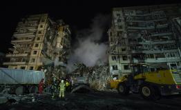 DNIPRO, UKRAINE - JANUARY 15: Firefighters stand near a dump truck while their colleagues are conducting search and rescue operations at residential building hit by a missile on January 15, 2023 in Dnipro, Ukraine.