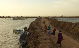 Internally displaced people walk along the road between the dykes into the Bentiu IDP camp