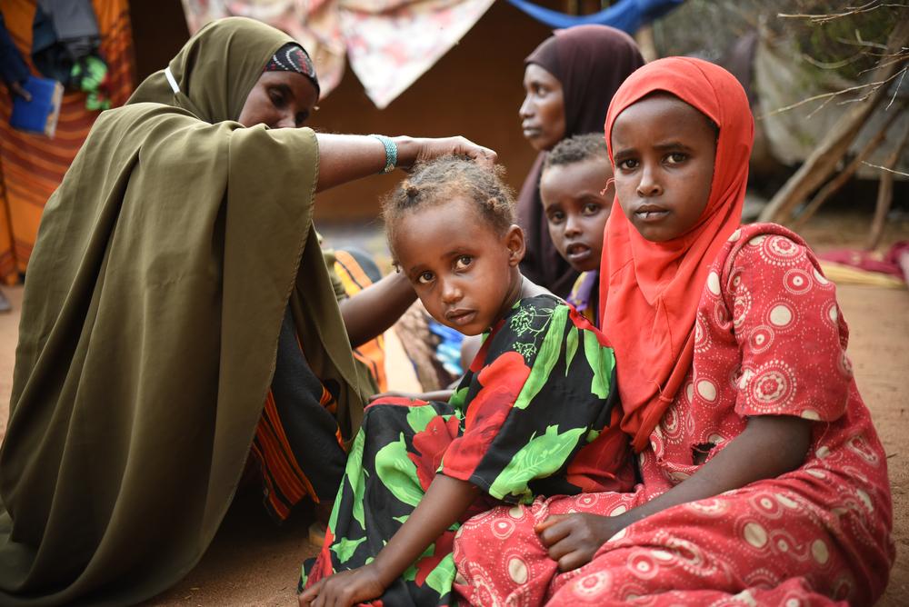 A little girl getting her hair done by her aunt in Dagahaley camp