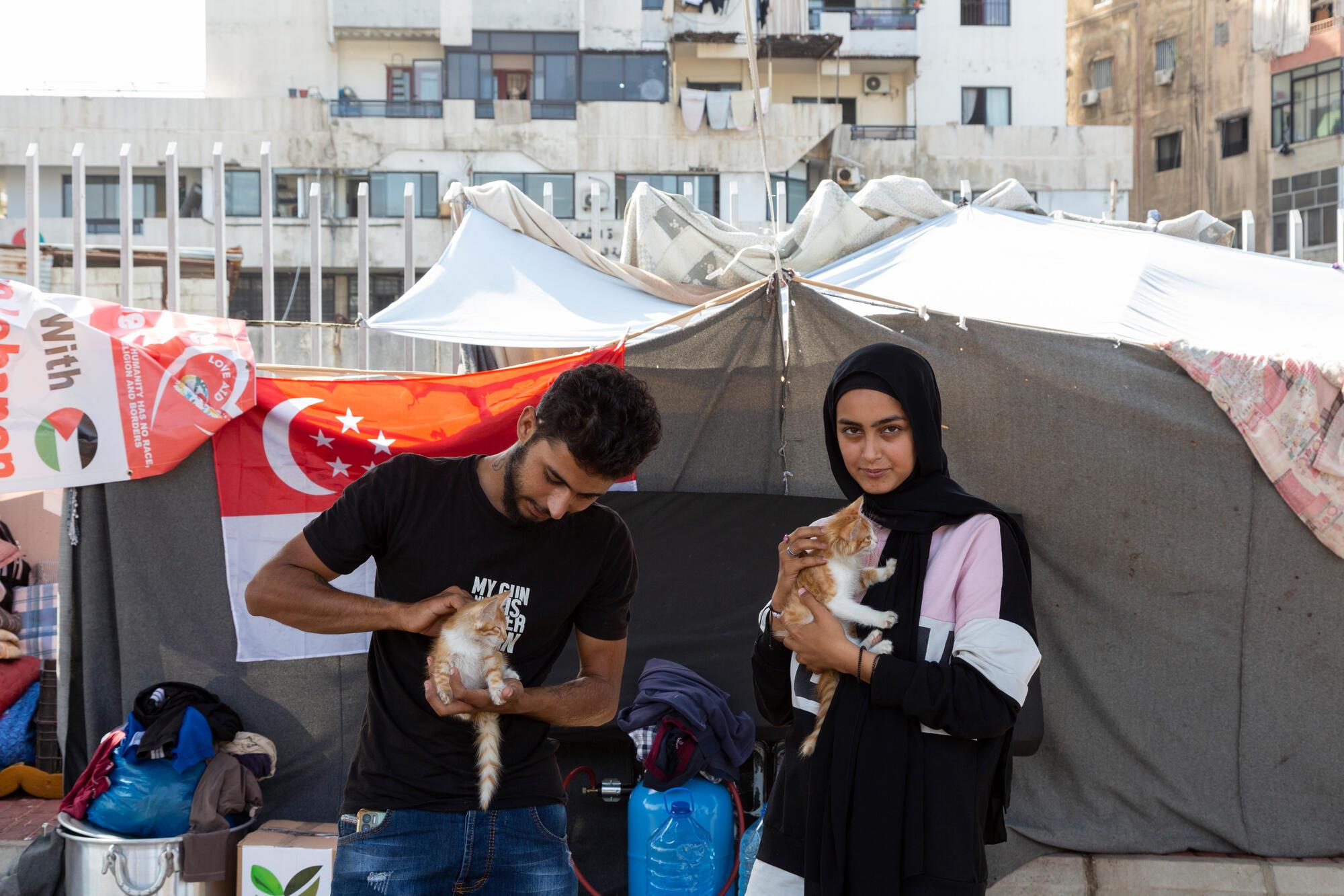 Kazem and his sister, Marimar, both Syrian refugees, hold their kittens in an informal displacement site in a parking lot in the city of Saida.