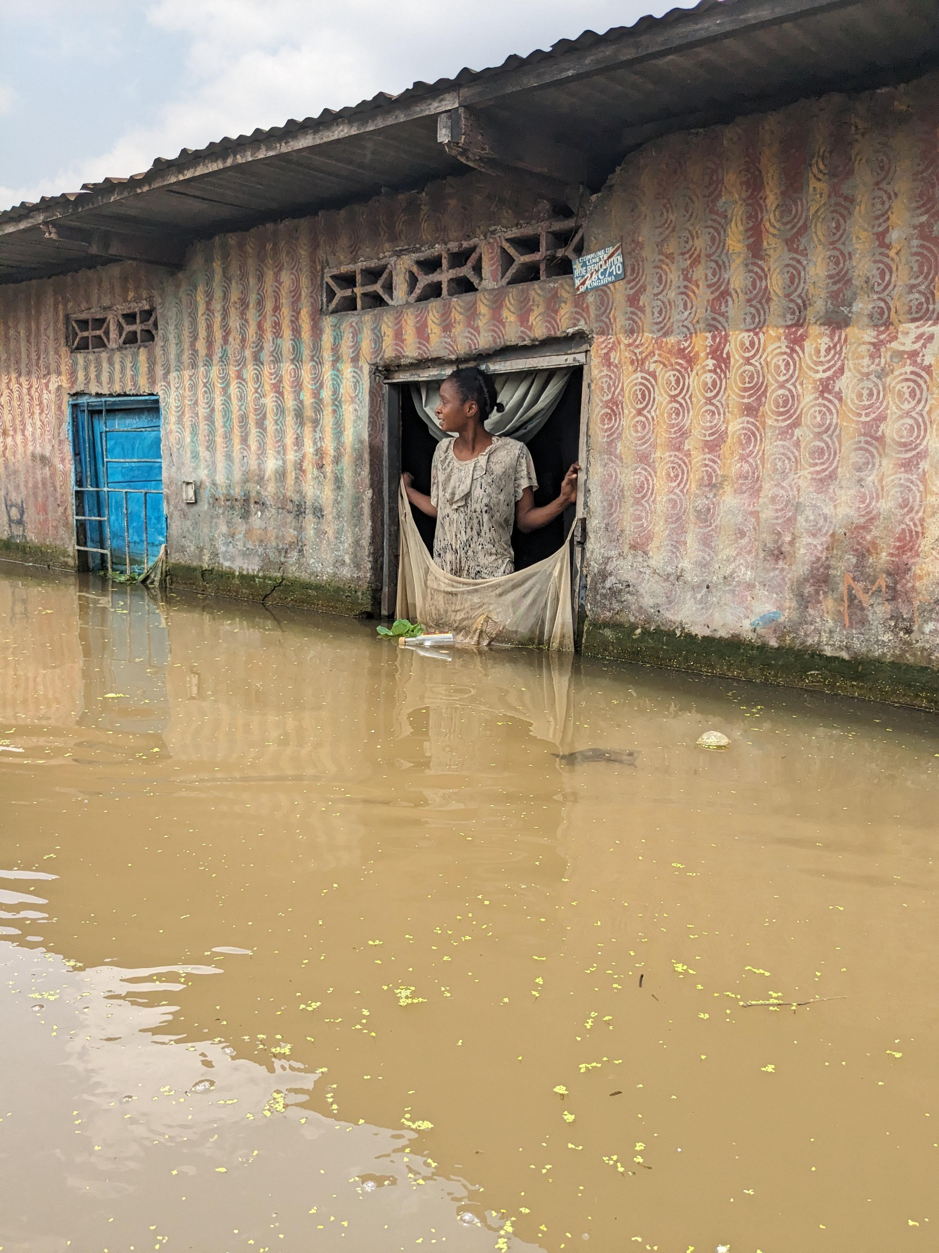 Julienne, a resident of the Kingabwa district in the commune of Limete, stands in front of her door, waiting for her children who have gone to school by canoe. 