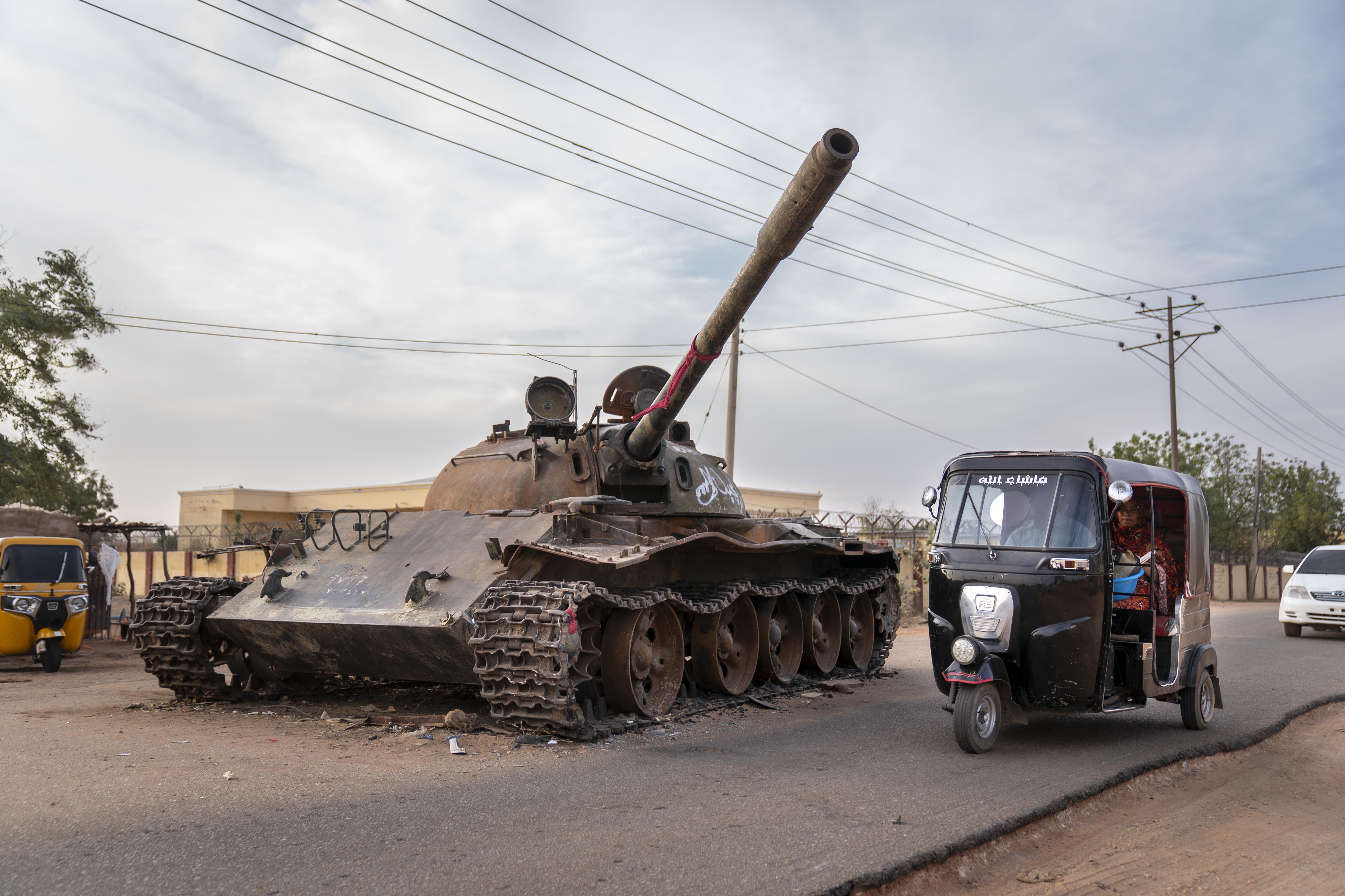 A rickshaw taxi goes around a destroyed tank belonging to the Sudanese Armed Forces.