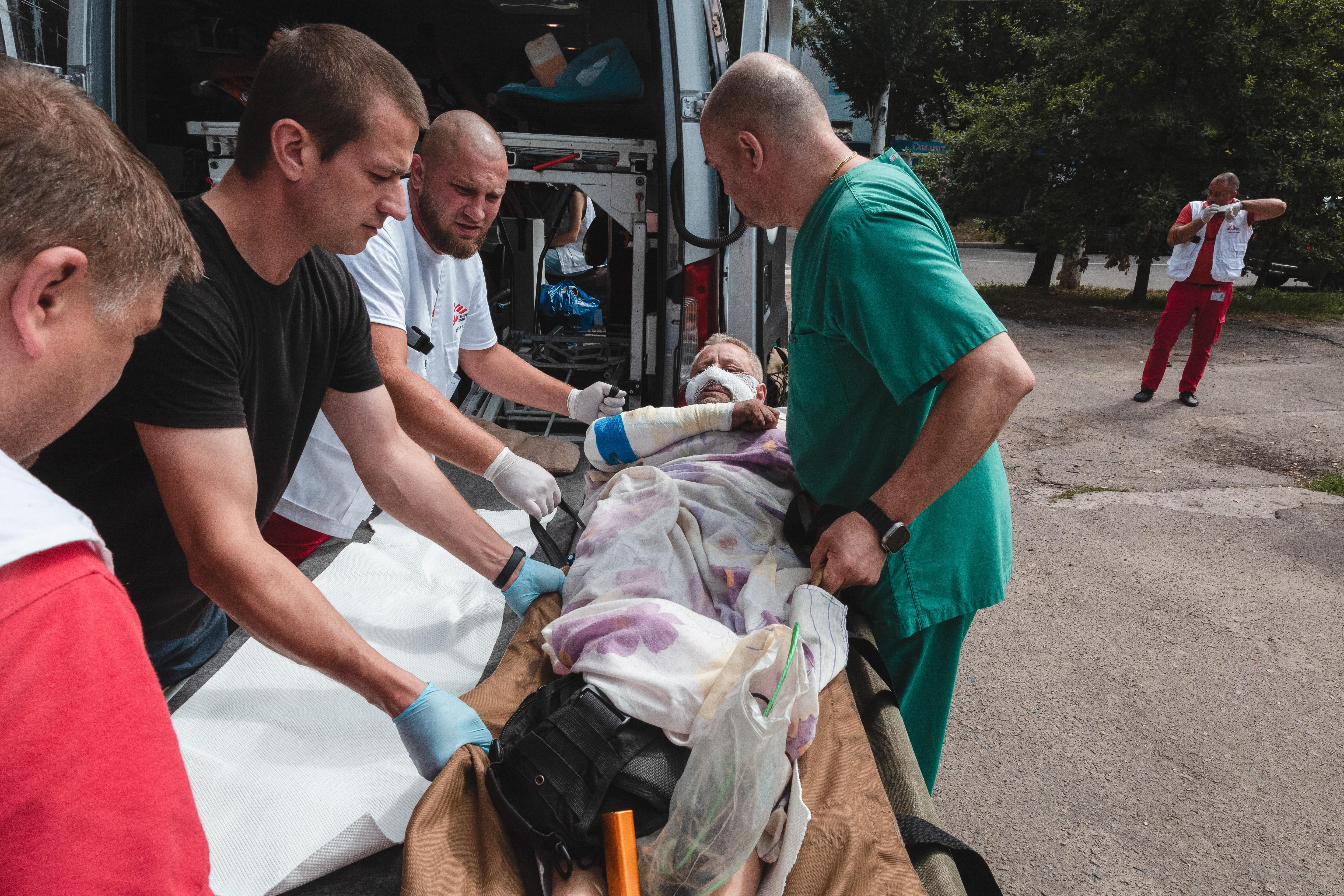 A patient with broken ribs and burns on his legs and hands is being prepared for transport. 