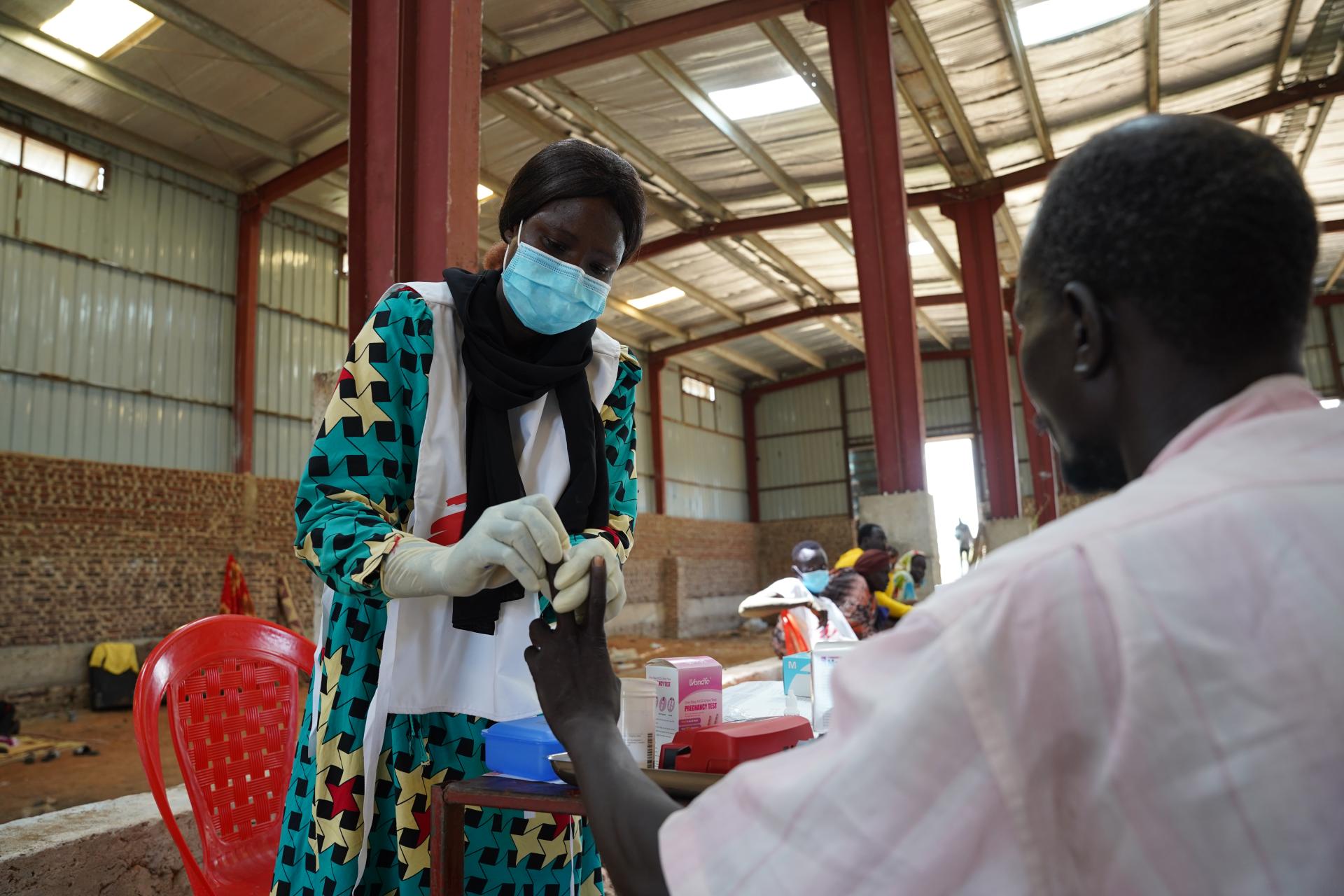 An MSF nurse, Regina Joseph, takes a blood sample for a rapid malaria test for Masakeel Deng,