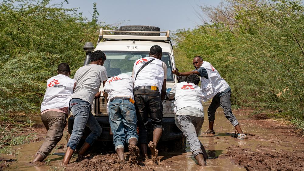 MSF staff pushing a vehicle that got stuck in the mud