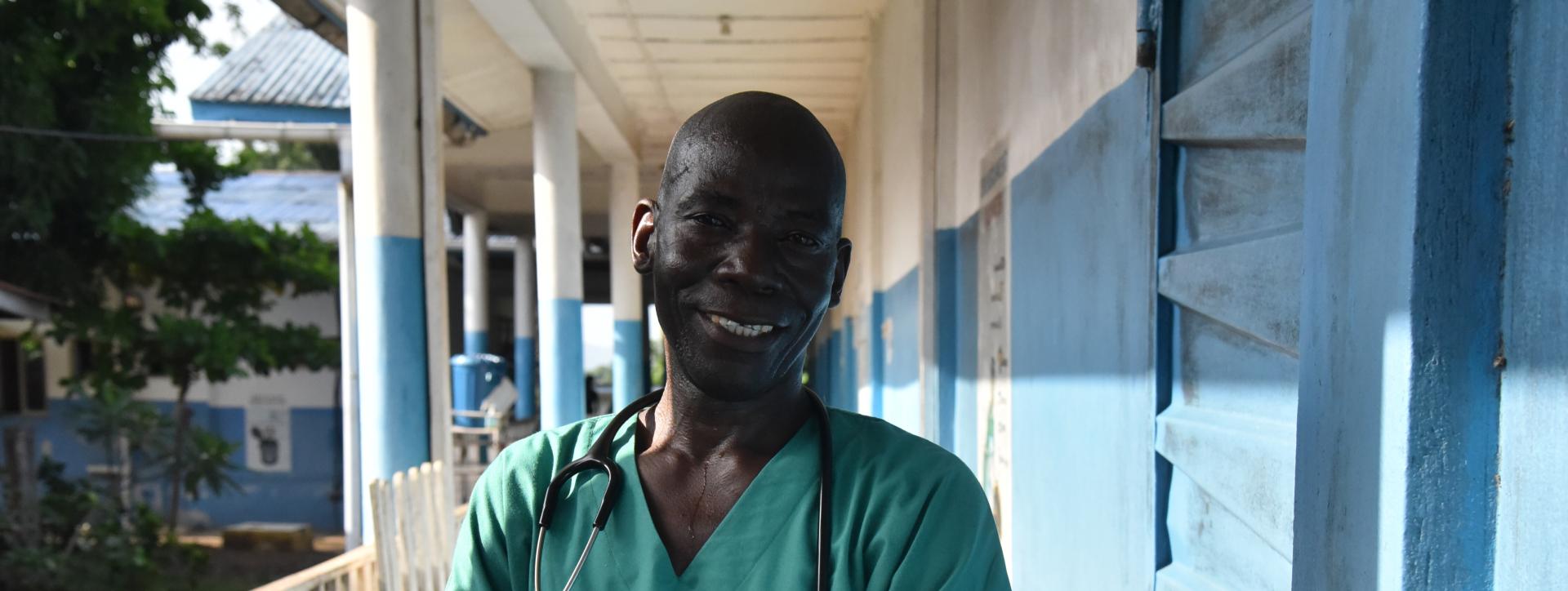 Community Health Officer Claude Ndoko standing outside the paediatrics unit of Magburaka government hospital, supported by MSF, in Tonkolili district, Sierra Leone.
