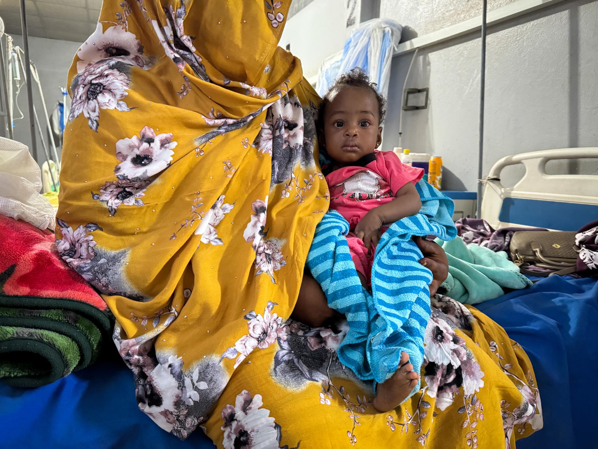 Ferdos holds her 11-month-old baby, Banan, who is infected with measles, in the isolation ward at El Geneina Teaching Hospital, which is supported by MSF. War forced Ferdos and her family to flee to El Geneina, where they live in overcrowded conditions with other families. Her son contracted measles and infected his 11-month-old daughter, who was unvaccinated.