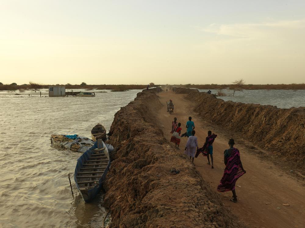 Internally displaced people walk along the road between the dykes into the Bentiu IDP camp