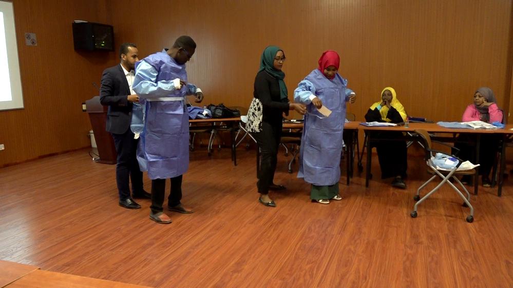 Sudanese healthcare professionals put on personal protection equipment during a training workshop 