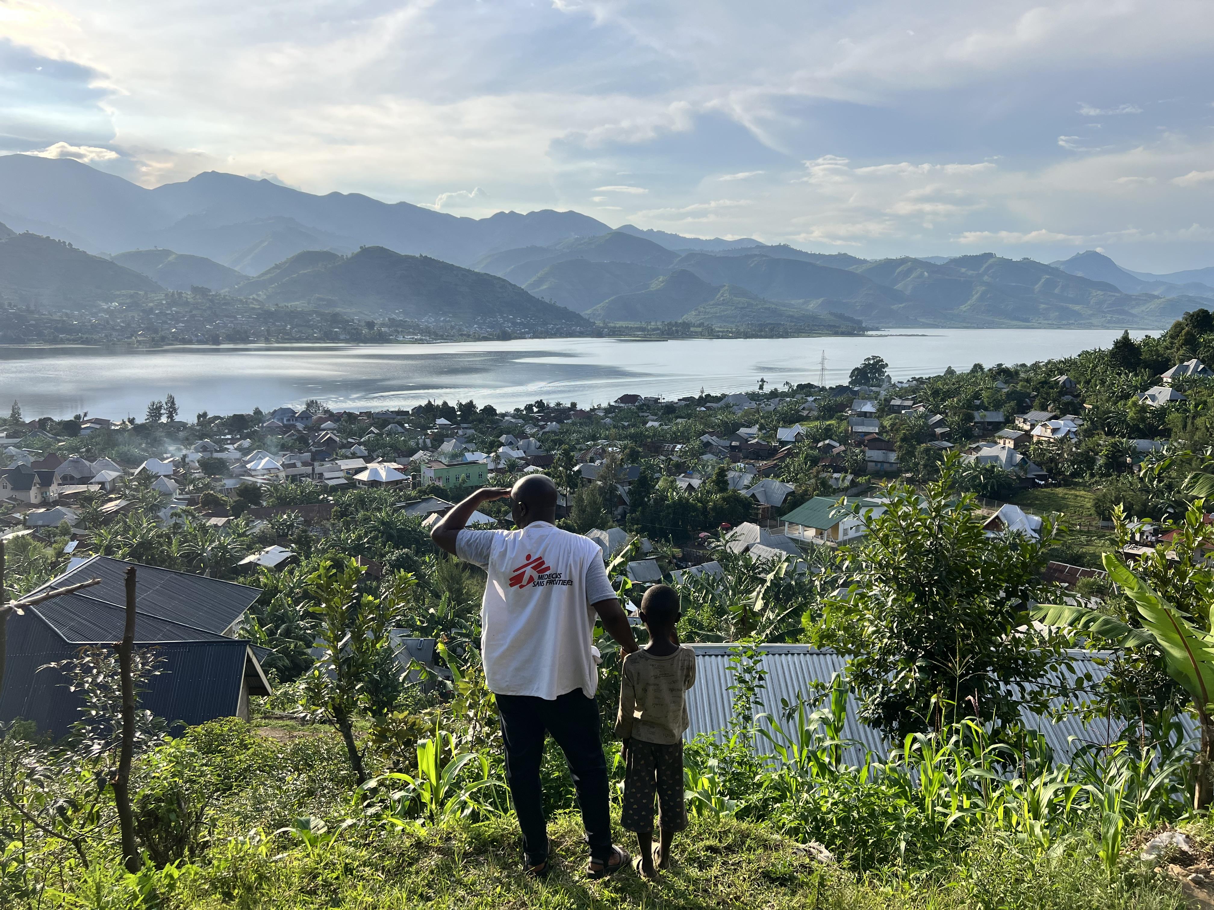 An MSF staff member and a child look at the town of Minova and Lake Kivu from the top of a hill. South Kivu province, eastern DRC