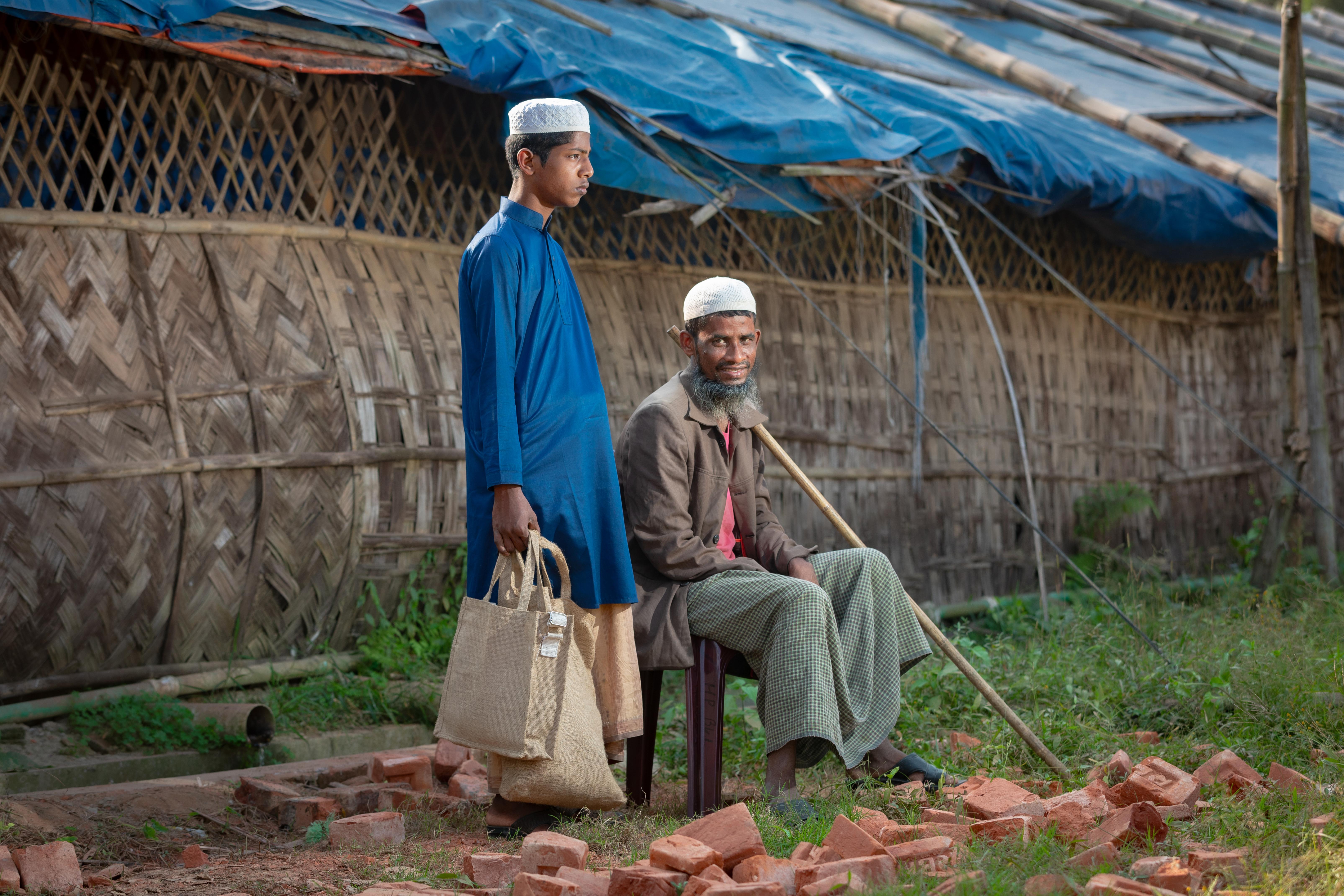 Abdulshakour sits while his son stands beside him