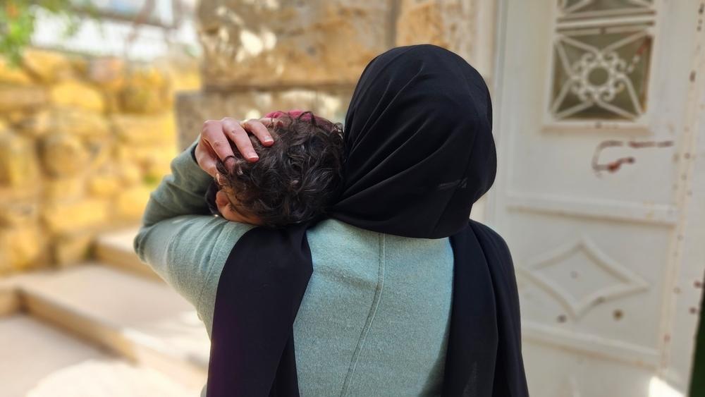 Aliyah*, a Palestinian woman holds her daughter tight in her arms
