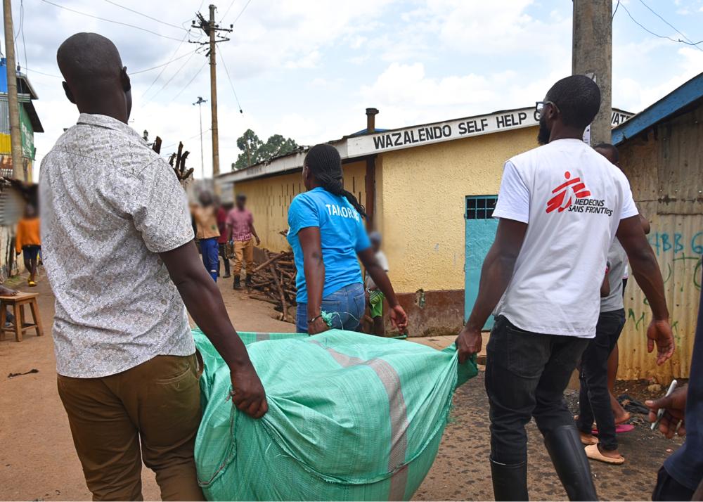 MSF team member and community members carry clothing to be distributed to children under ten years