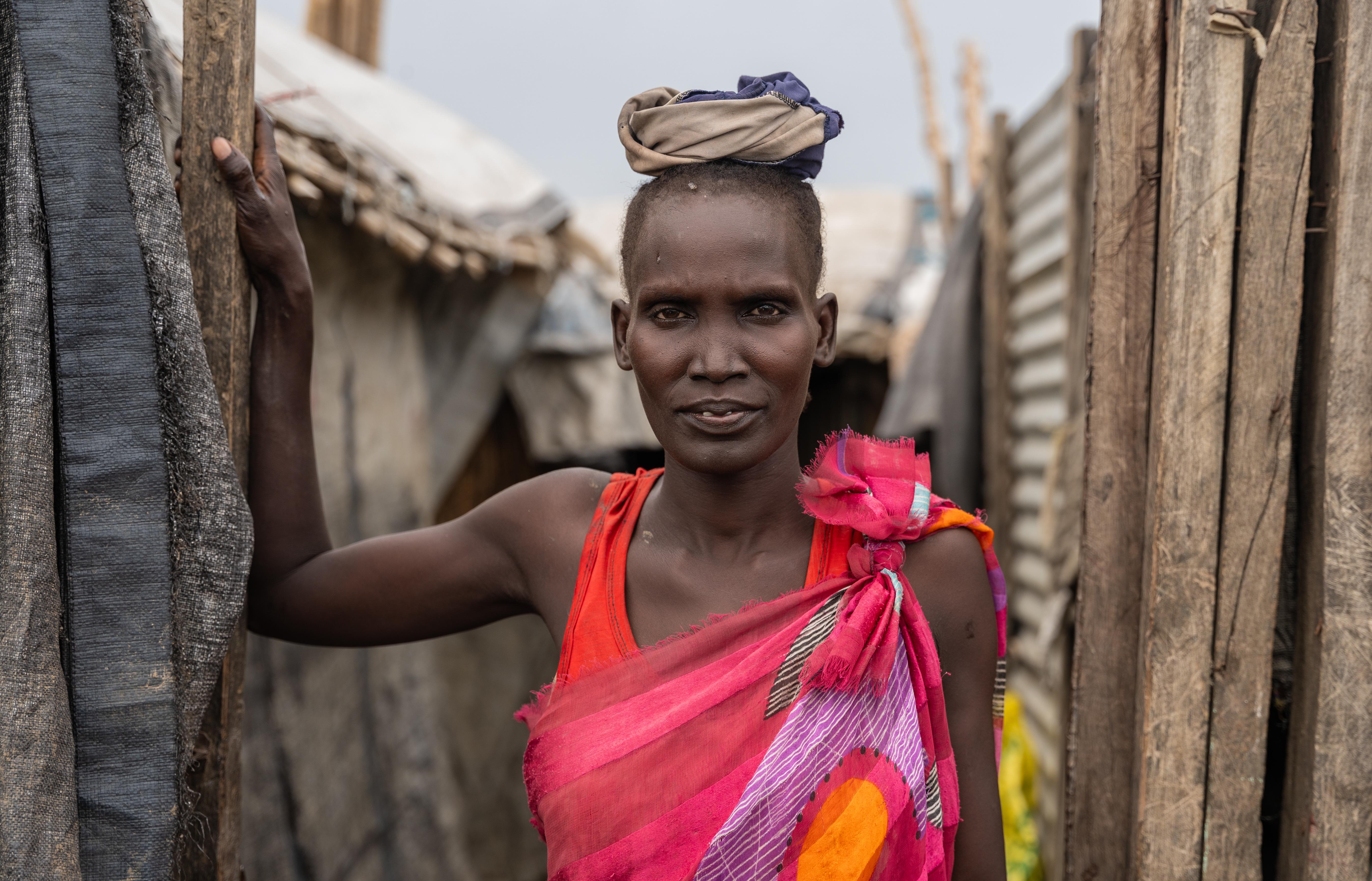 Nyachany Biliew, 30-year-old, poses in front of her shelter made from brittle wood and plastic sheets, where she lives with her 6 children