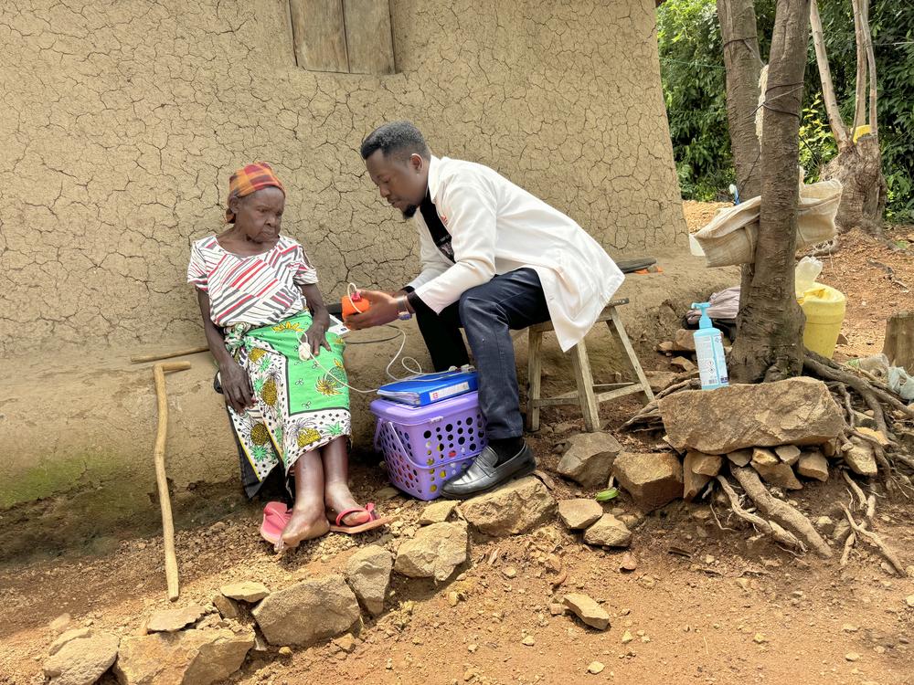 Victor Oriema, MSF supported MOH palliative care nurse checks the vitals of Monica Anyango Onduko