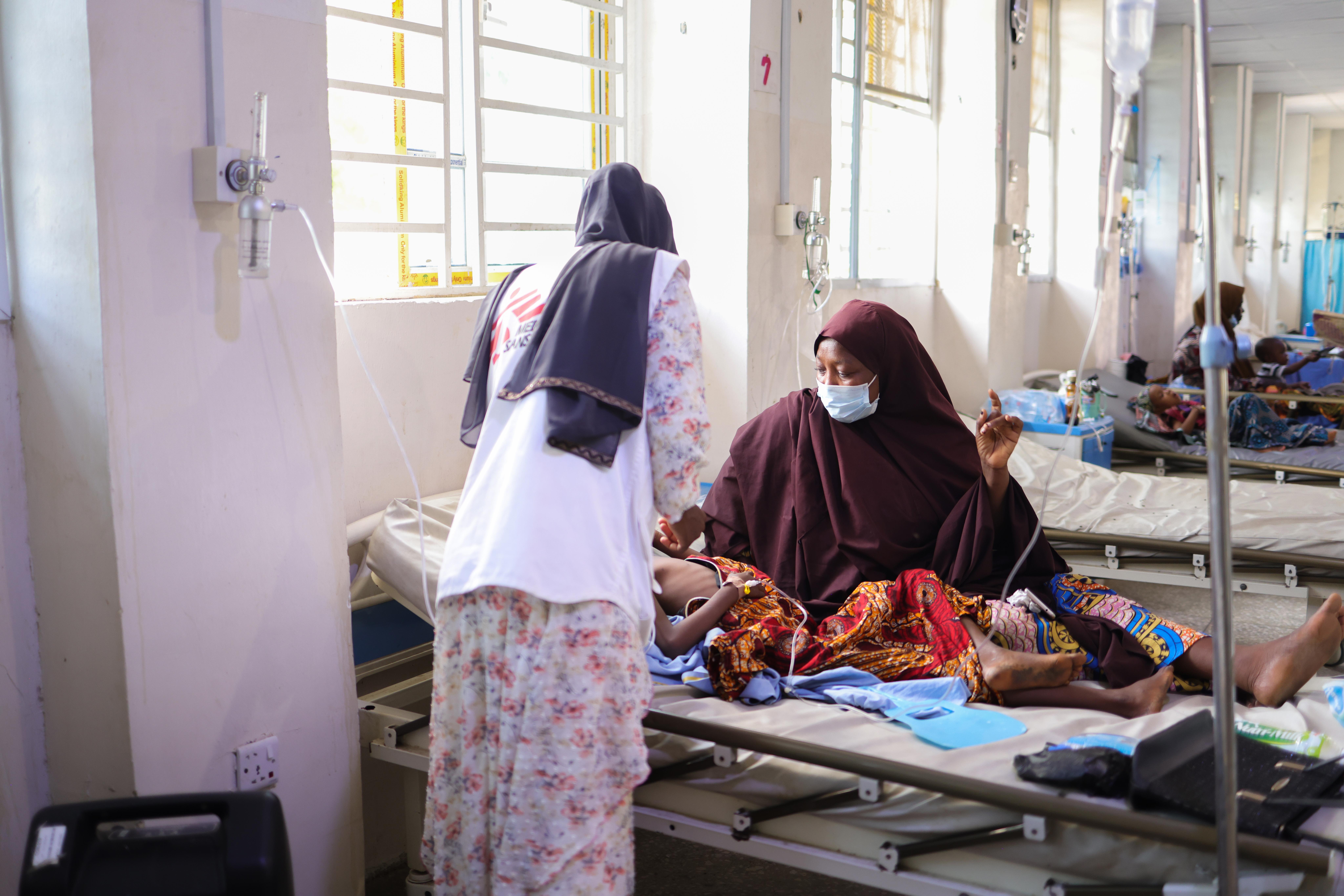 MSF Medical Activity Manager Khadeejah Usman helps Halisa Mahmud adjust the position of her 11-year-old daughter Halima Arma. Halisa is on admission for diphtheria at the Intensive Care Unit of the Infectious Diseases Hospital, Kano state, northwest Nigeria.