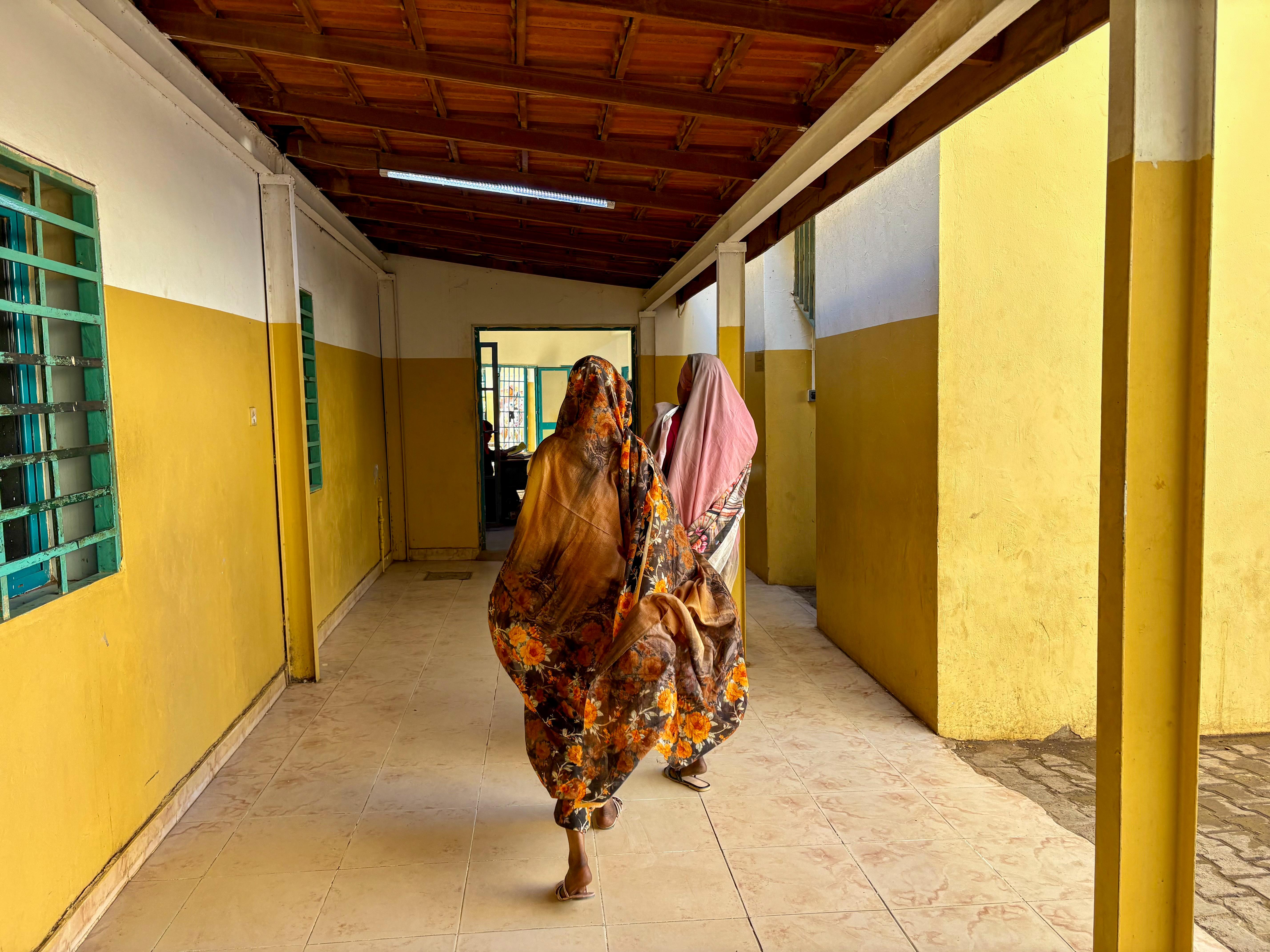 Two women are walking through a corridor in the hospital.