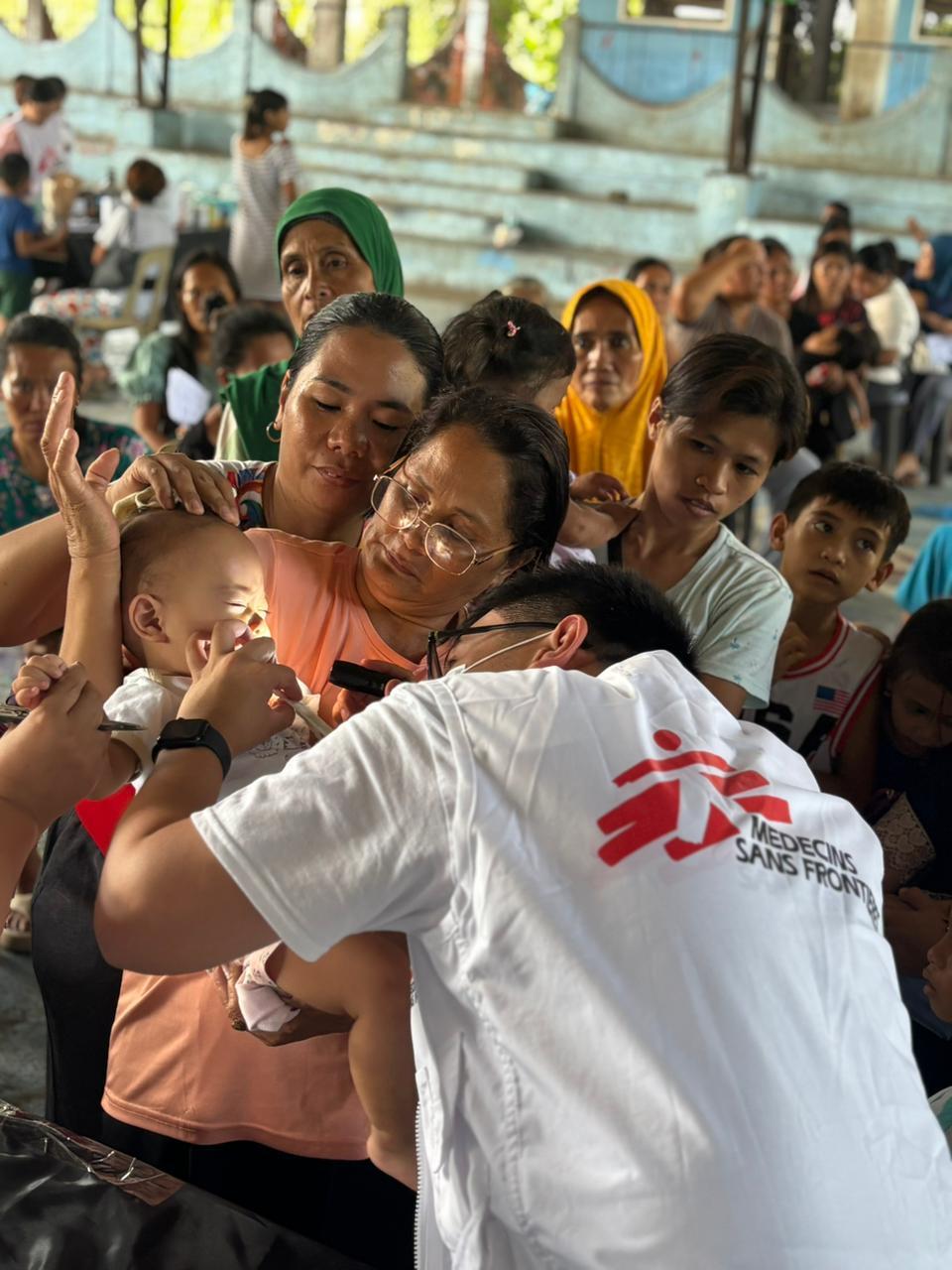 A health worker attends to a child at a mobile clinic set up inside a covered basketball court in Sarangani Province, Mindanao, Philippines.