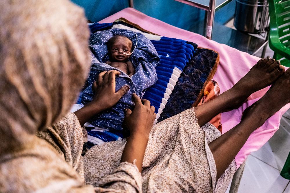 Sedra Adam Ali looks at her 20 week old baby girl in the neonatal intensive care unit (NICU). Sedra was diagnosed as having eclampsia and doctors carried out an emergency cesarian section to ensure a safe and successful delivery of her baby who was delivered at 7 months. 25 July, Zalingei, Centeral Darfur.