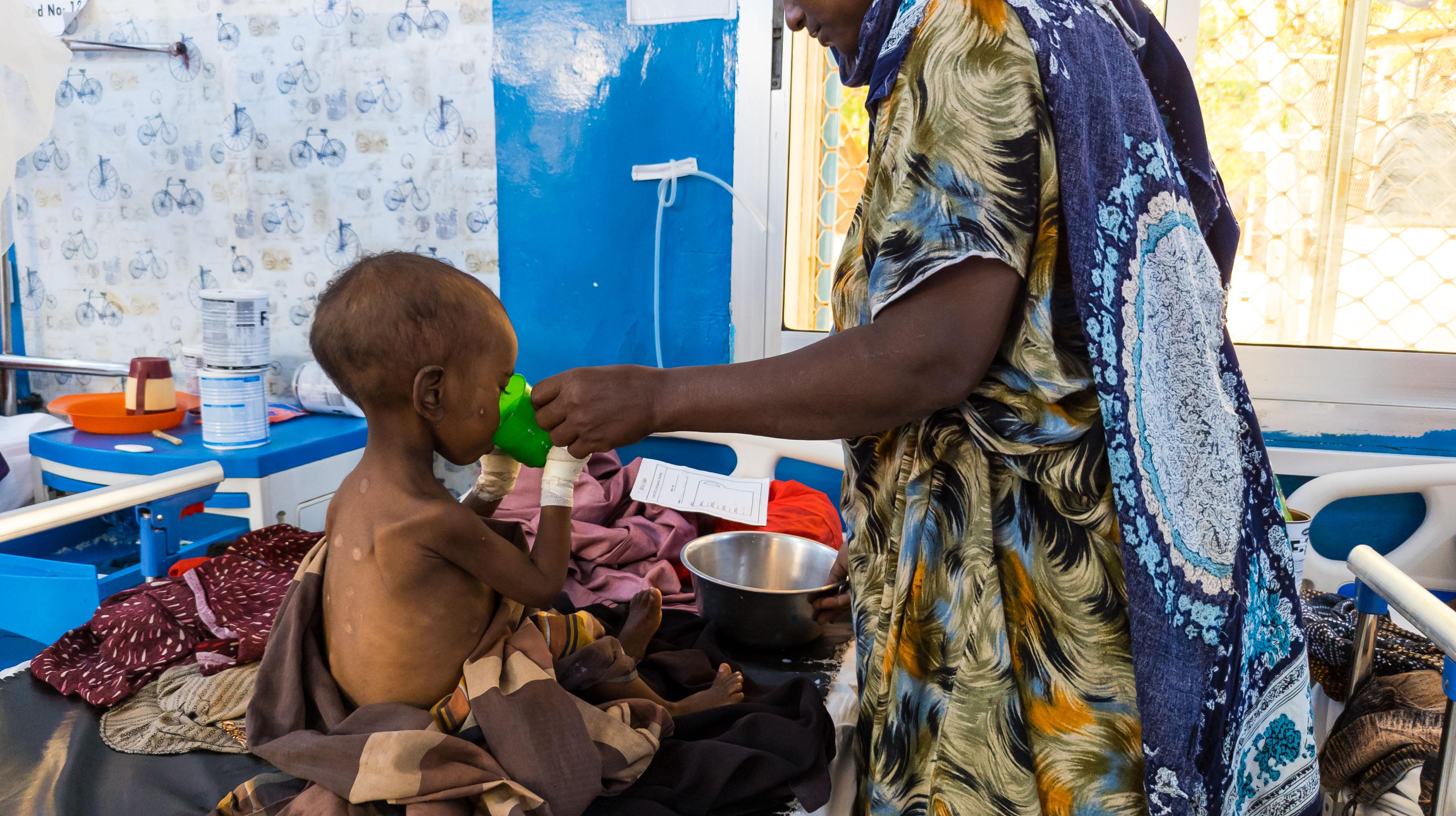 A Mother feeds her severely malnourished son with therapeutic milk in the Inpatient Therapeutic Feeding Centre (ITFC) ward at the MSF-supported Bay Regional Hospital in Baidoa, Somalia. Therapeutic milk is a high-nutrient formula used to treat children with severe acute malnutrition.